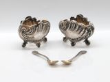 pair of silver plated spoons and spoon rest on a white surface