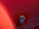 a close up of a red car with a badge on it