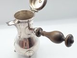an antique silver coffee pot with a wooden handle on a white surface