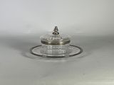 un plateau en argent muni d'un couvercle en verre et d'une soucoupe posée dessus