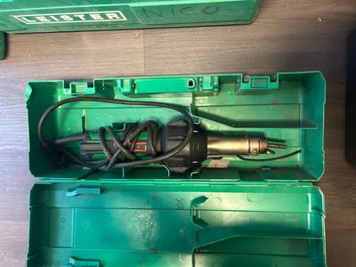 a green box with a drill in it on the floor