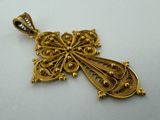 a close up of a gold cross pendant on a white surface