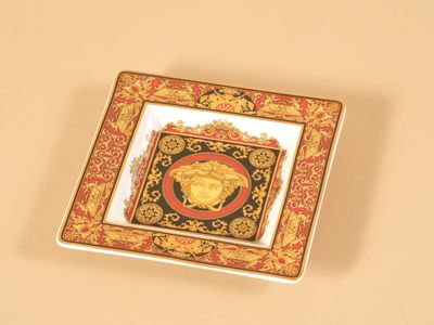 une assiette dorée et rouge sur laquelle est représentée une tête