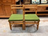 two wooden chairs with green cushions on them in a room