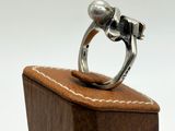 silver ring with two skulls on a wooden stand