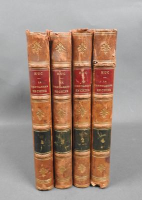 three old books are stacked on top of each other on a gray surface