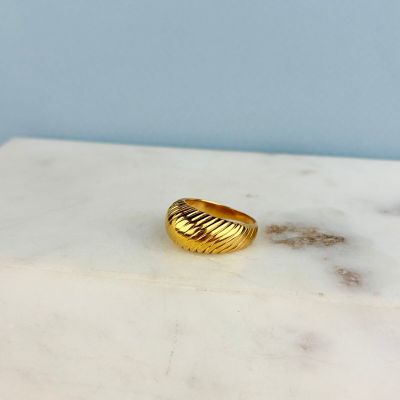 La bague en or repose sur une table en marbre.