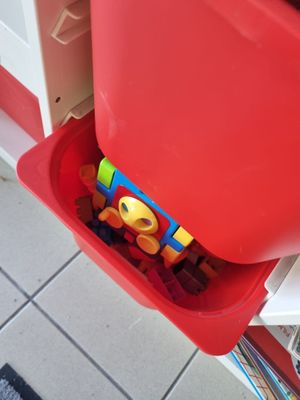 un bac rouge posé par terre, contenant des jouets