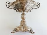 a silver cup on a stand on a white wall
