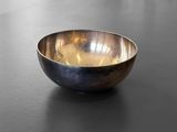 a metal bowl sitting on a table with a black surface