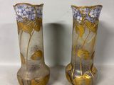 pair of vases with flowers and leaves on them on a white surface