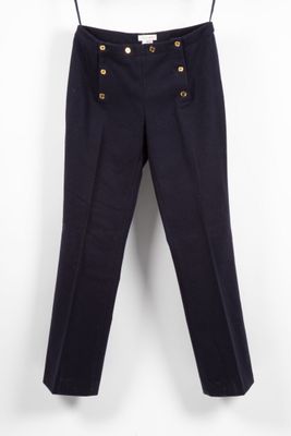a black pants with gold buttons hanging on a hanger