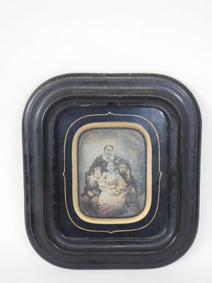 an old picture of a woman holding a baby in a black frame