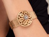 a close up of a woman wearing a gold bracelet with a diamond