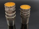 two silver cups with coins on them sitting on a black surface