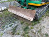 a green and yellow bulldozer sitting in the grass