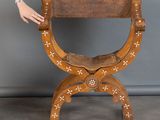 une personne tendant la main vers une chaise en bois ornée de croix