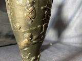 a bronze vase sitting on top of a wooden base