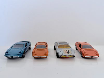 quatre petites voitures sont alignées sur une surface blanche