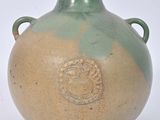 un vase vert et marron muni d'anses, sur fond blanc