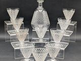 six clear glass wine glasses and a decanter on a clear stand