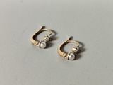two pairs of earrings with pearls on them sitting on a table