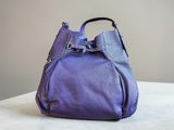 a purple handbag sitting on top of a table next to a wall