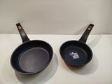 pair of black frying pans sitting on top of a white counter