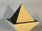 objet de forme pyramidale, jaune et noir, posé sur une surface blanche