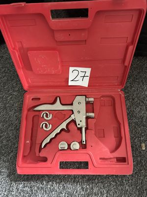 une boîte à outils rouge ouverte, contenant des outils, posée sur un tapis