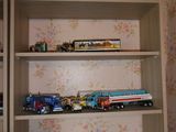 de nombreux camions miniatures et camions posés sur une étagère dans une pièce