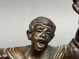 a bronze statue of a boy with his hands in the air