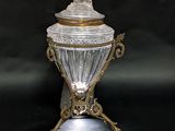 an antique silver and glass covered jar with a bird on top