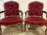 pair of red upholstered chairs with ornate carved arms