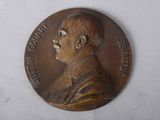 an old bronze medal with a man ' s face on it