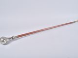 an antique silver plated stick with a wooden handle on a white surface