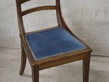 a wooden chair with a blue seat on a concrete floor