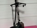 une image représentant un aspirateur noir et argenté posé sur une surface rose