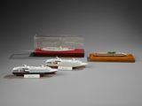 three miniature model ships are on display on a gray surface