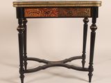 une image représentant une petite table avec un piètement noir et un motif rouge et doré
