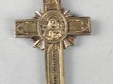 a silver cross with a red ribbon around it