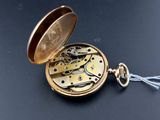 an image of a gold pocket watch with a chain on a black surface