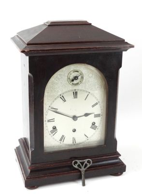 une petite horloge en bois à laquelle est attachée une clé