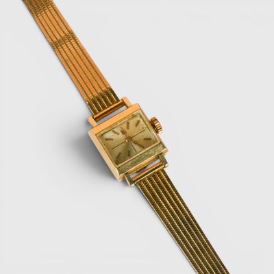une image représentant une montre de couleur dorée au cadran carré