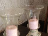 two glass vases with pink candles on a wooden table