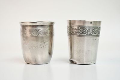 deux tasses en argent posées l'une à côté de l'autre sur une table