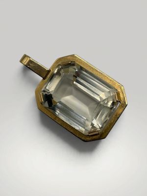 un gros plan d'un pendentif en tourmaline verte sur une surface blanche