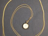 une image représentant un collier en or avec une montre suspendue à une chaîne