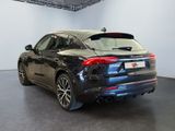the rear end of a black car parked in a showroom