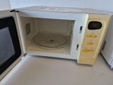 un micro-ondes posé sur un plan de travail, avec une casserole à l'intérieur